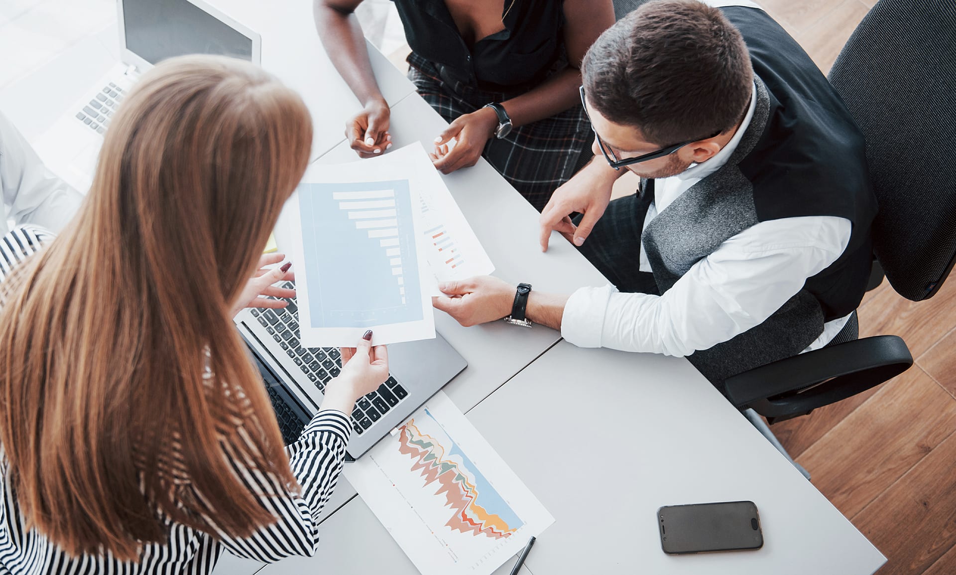 Trois collaborateurs analysent des graphiques de rémunération autour d'une table de réunion