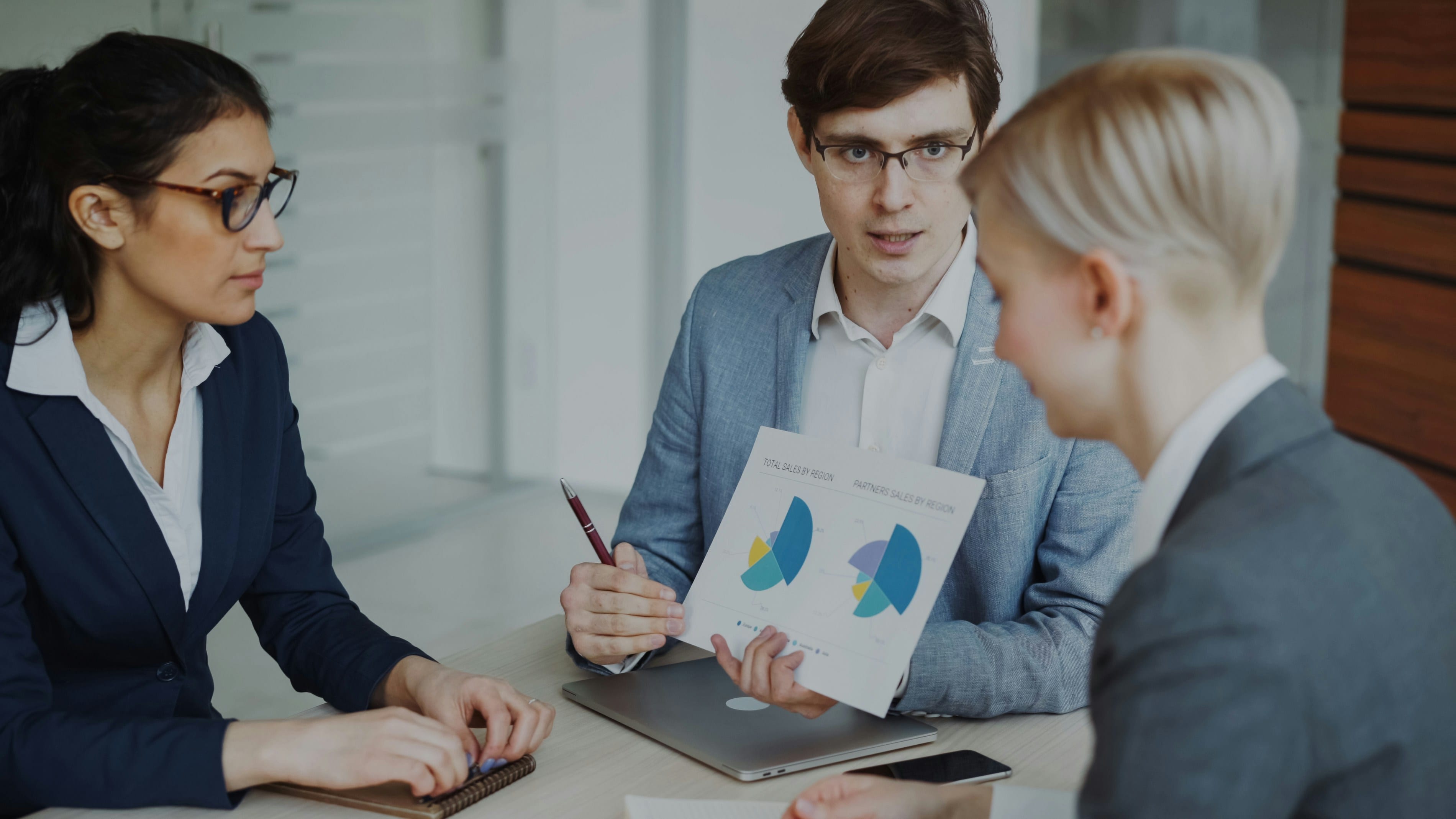 Trois professionnels en réunion autour d'un rapport d'analyse